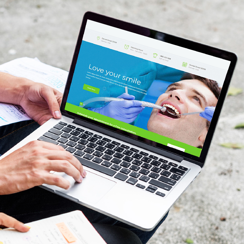 A person having laptop on his lap and viewing dental website 