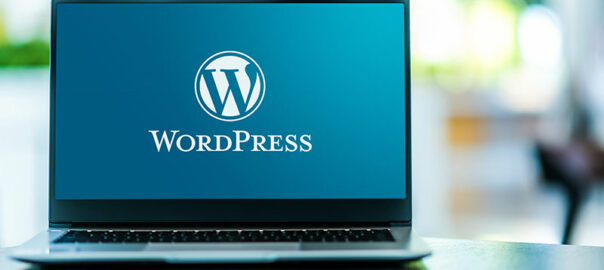 A laptop is kept open and the screen is showing wordpress welcome page.