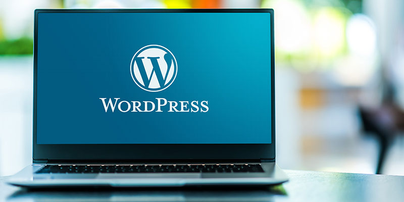 A laptop is kept open and the screen is showing wordpress welcome page.